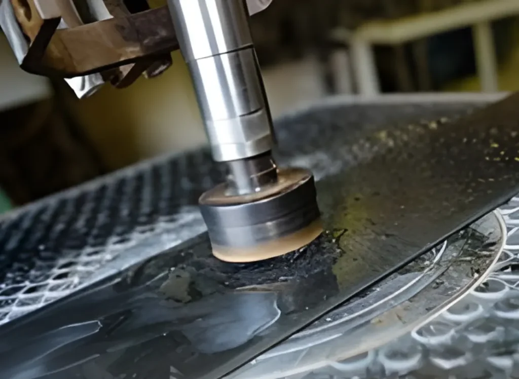 A machine buffs away at the surface of a metal sheet.