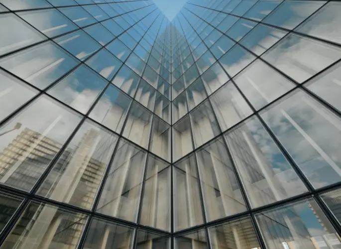 The sun reflects off of several glass windows in a skyscraper.