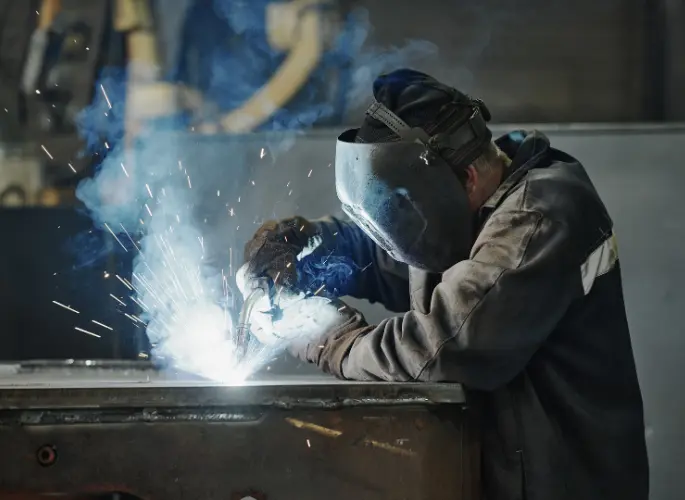 A metalworker solders two pieces of metal together.