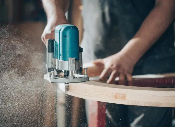 A furniture maker sands down the edge of their project.
