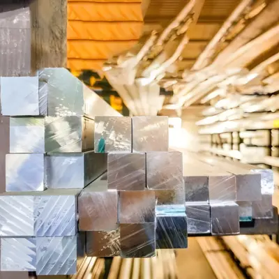 Several square bar extrusions are stacked on a shelf.