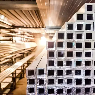 Several square tube extrusions are stacked on a shelf.