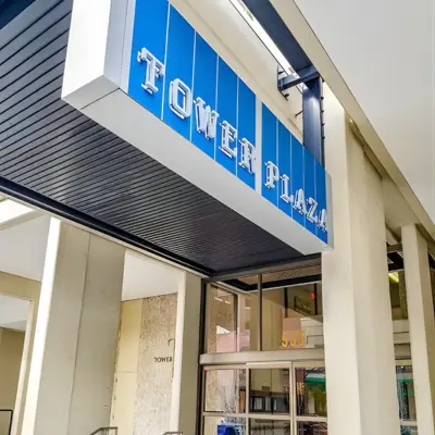 White metal letters on a blue background spell "Tower Plaza."