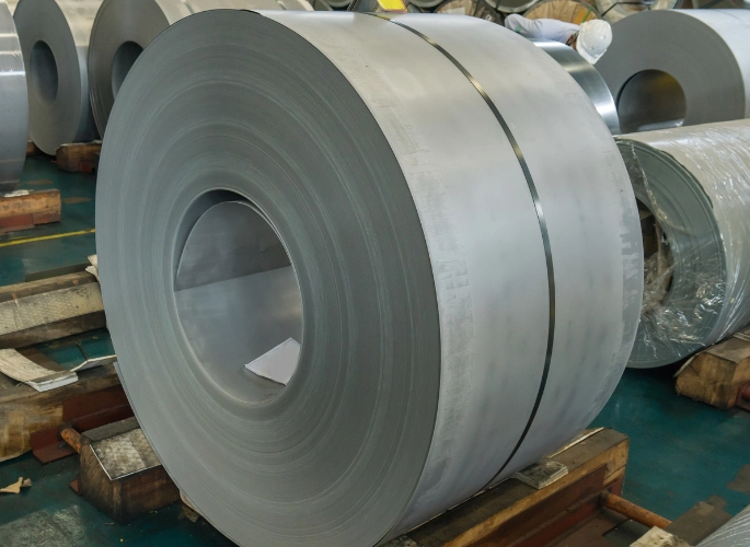 Several hot-rolled steel sheet coils rest in a warehouse